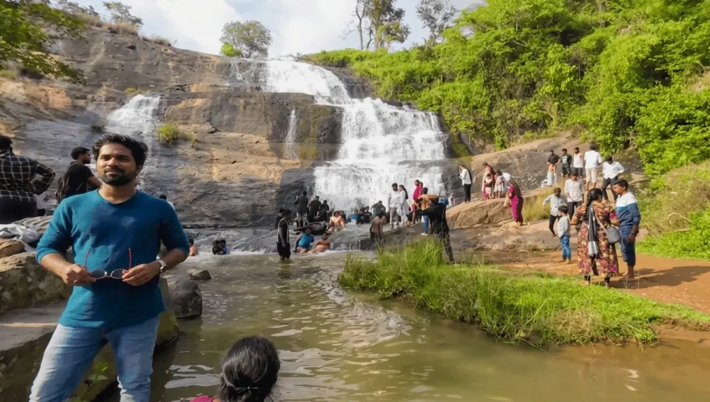 Wide view of Chapurai Waterfalls in Araku Valley Andhra Pradesh with rocky cascade and tourists relaxing in clear water, one of the 11 best places to visit in april in india
