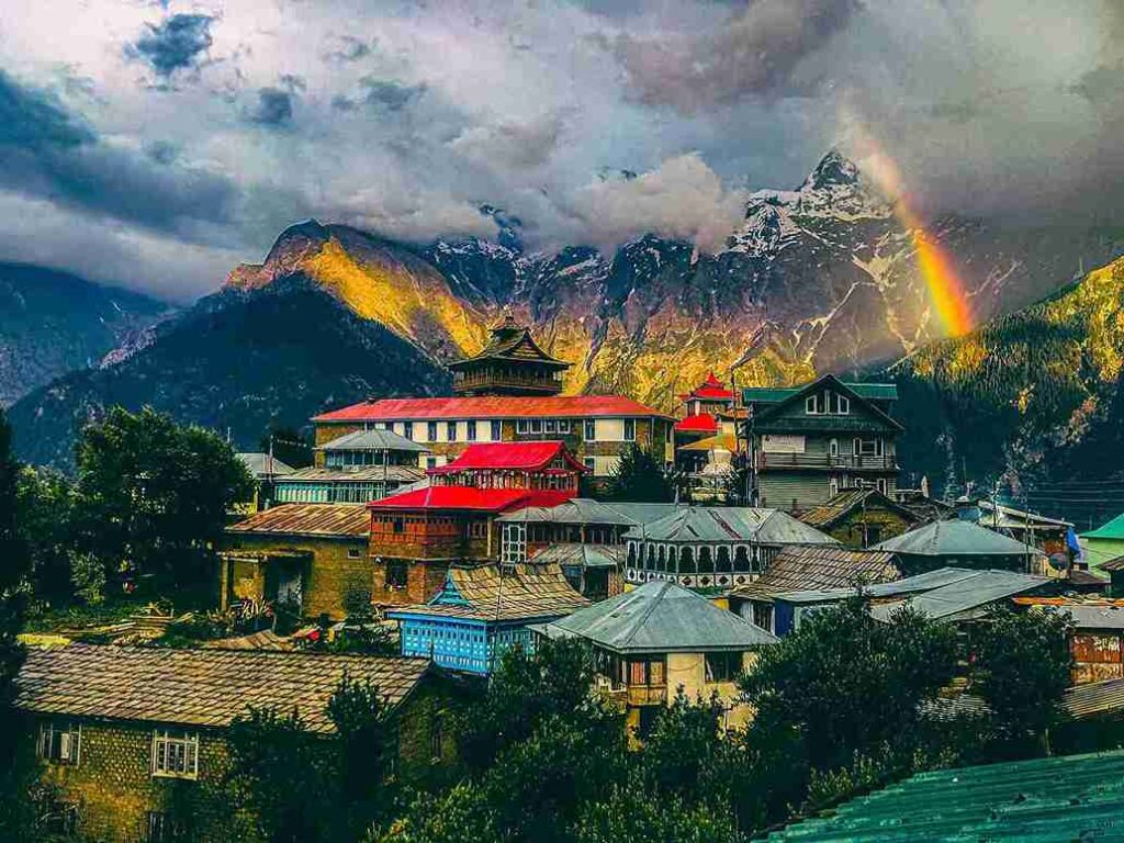 Scenic view of Kalpa village in Himachal Pradesh with wooden houses, rainbow and Kinnaur Kailash mountains, one of the 11 best places to visit in april in india