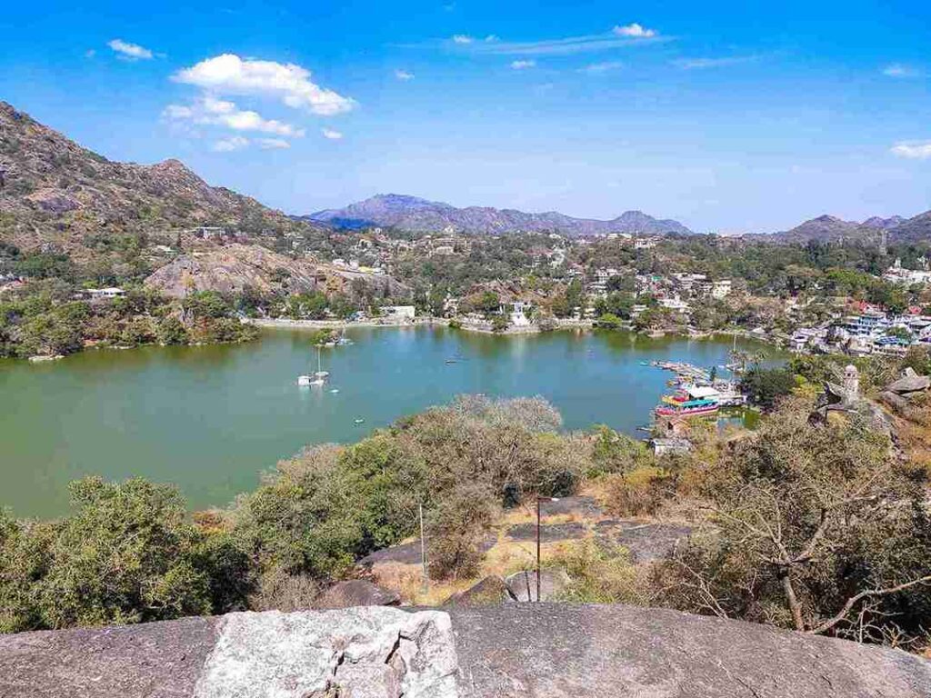 Wide-angle view of Nakki Lake in Mount Abu Rajasthan with boats, green trees and Aravalli hills, one of the 11 best places to visit in april in india