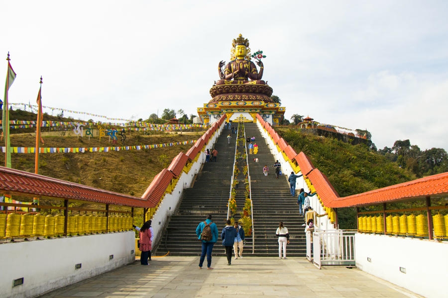 Giant golden Buddha statue at Buddha Park Ravangla near Pelling Sikkim with prayer flags and tourists, one of the 11 best places to visit in april in india