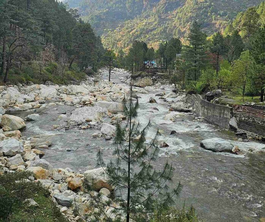 An aerial view of a clean, secluded riverside homestay in Tirthan Valley, Himachal Pradesh, featured as one of the best places to visit in May in India 2026 for riverside relaxation.