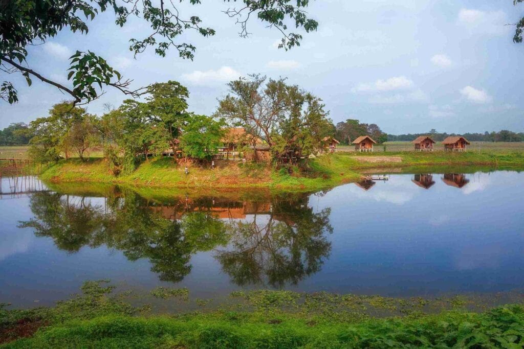 Traditional bamboo stilt houses reflected in the calm waters of Majuli Island, Assam, featured as one of the best places to visit in May in India 2026 for a unique cultural experience.