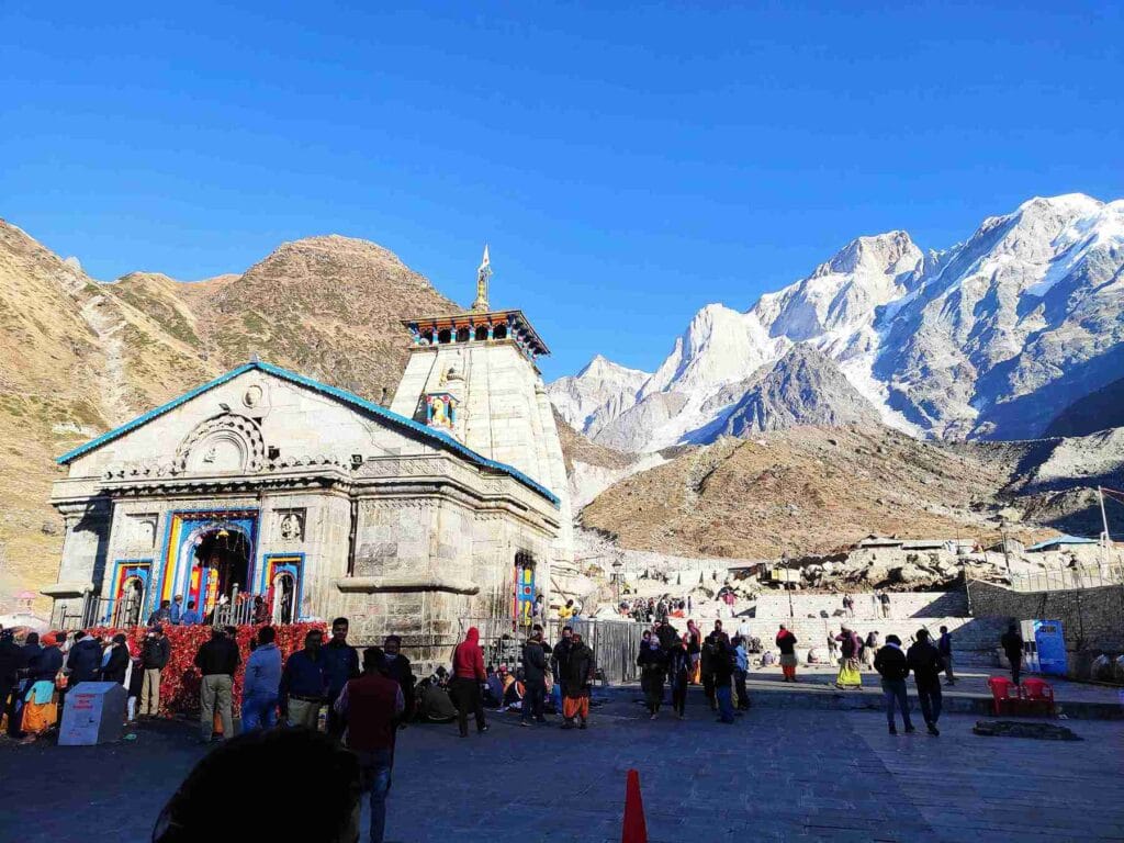 Crowds gathered outside the historic Kedarnath Temple with the snow-covered Himalayan peaks in the background, a key highlight of our Kedarnath trip budget guide for 2026.