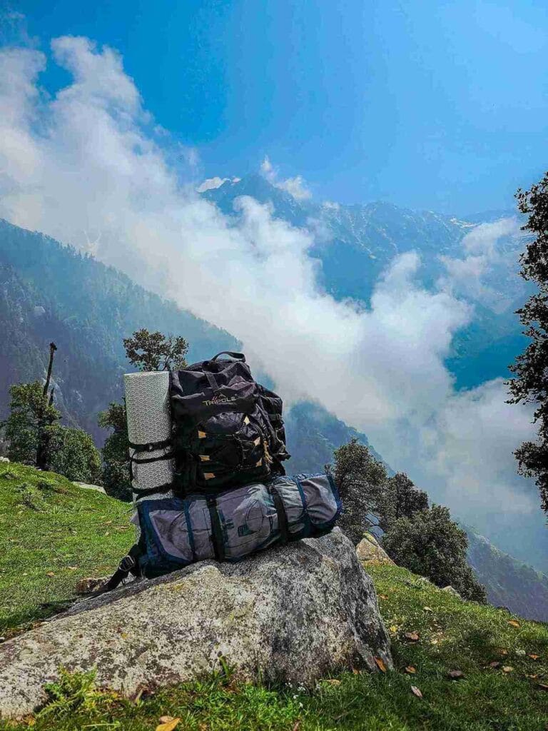 Trekking backpack with essential gear on a mountain cliff for Kedarnath budget trip packing list 2026.