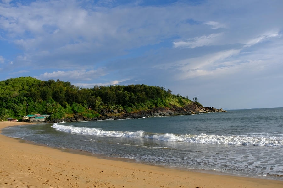 Scenic view of a Gokarna beach, one of the best places to visit in India, featuring golden sands, tropical greenery, and the Arabian Sea.