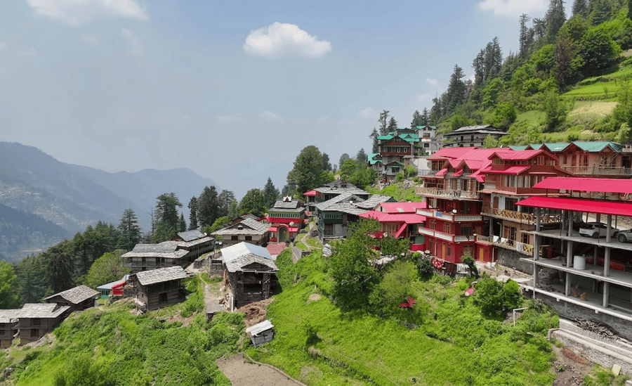 A clean, scenic view of the colorful houses and lush green hills of Shoja village, recognized as one of the 13 best places to visit in August in India 2026."
