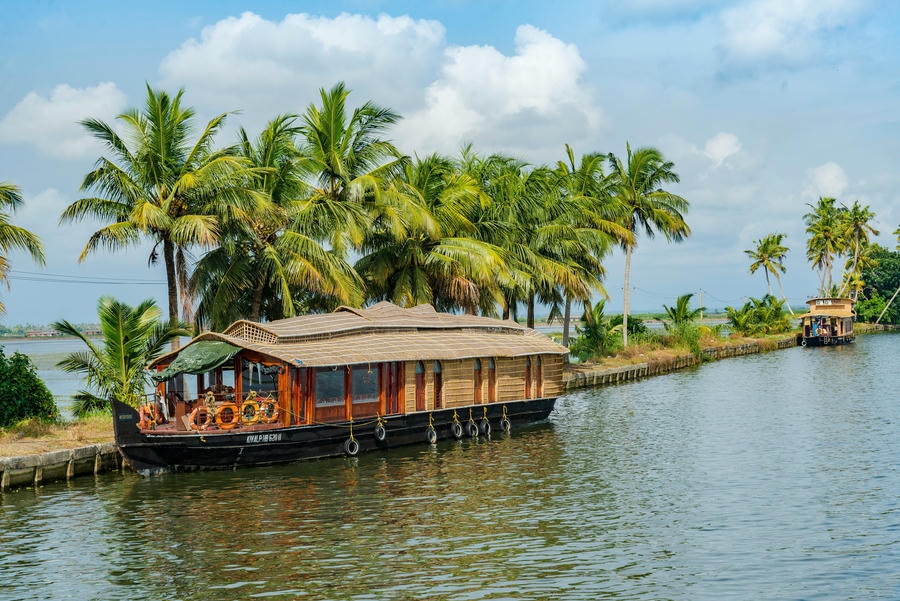 A traditional thatched-roof houseboat cruising through the scenic, palm-fringed backwaters of Kerala, featured in our guide to the 21 best places to visit in south.