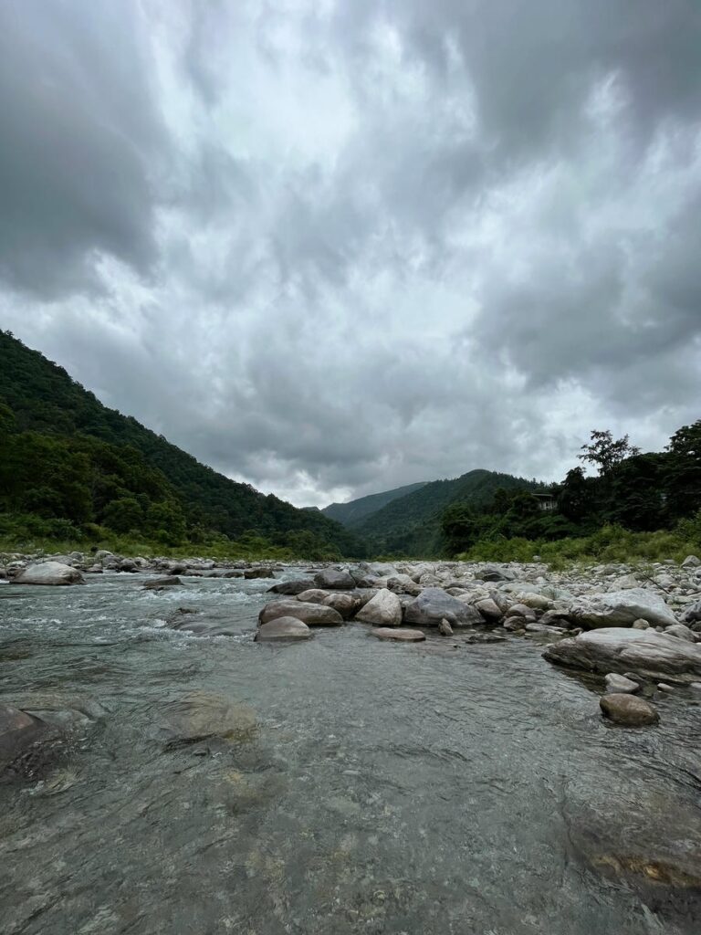 A wide-angle view of a rocky riverbed and lush mountains in Almora, Uttarakhand, one of the 15 best places to visit in November in India 2026.
