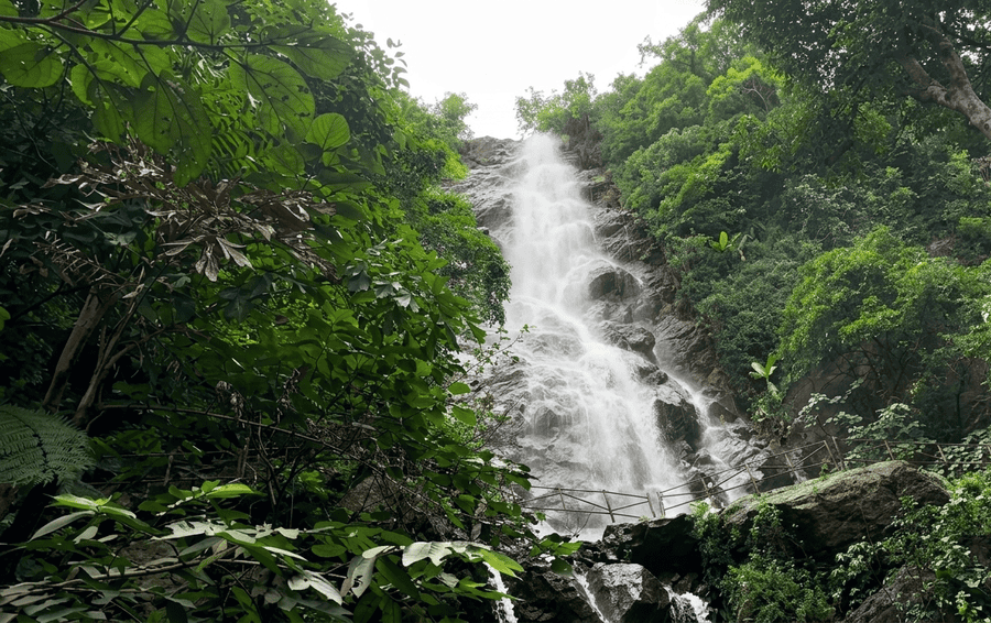 Powerful white stream of water flowing down rocky cliffs framed by dense jungle foliage in Araku Valley, highlighted among the best places to visit South India.