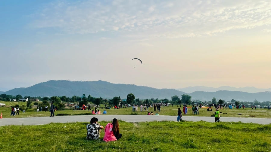 People relaxing at the paragliding landing site in Bir Billing with mountains in the background, ranked among the 15 best places to visit in November in India 2026.