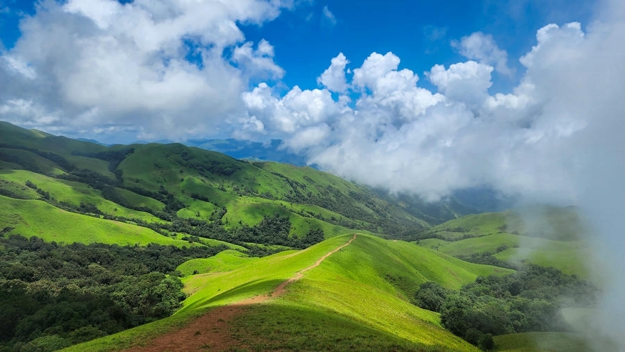 The lush green rolling hills of Chikmagalur under a cloudy sky, one of the 15 best places to visit in November in India 2026.