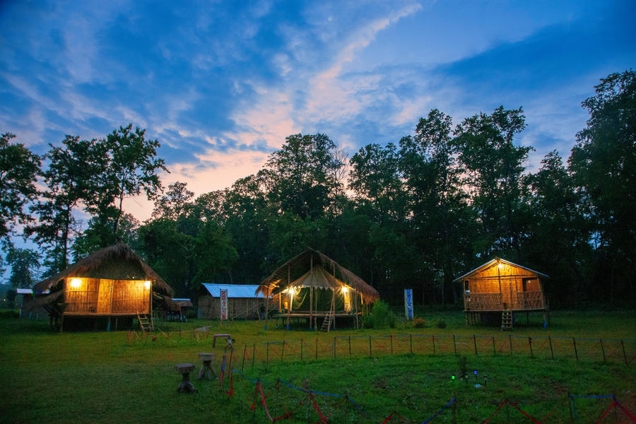Eco-friendly bamboo cottages in Majuli, Assam, under a twilight sky, recognized as one of the 15 best places to visit in November in India 2026.