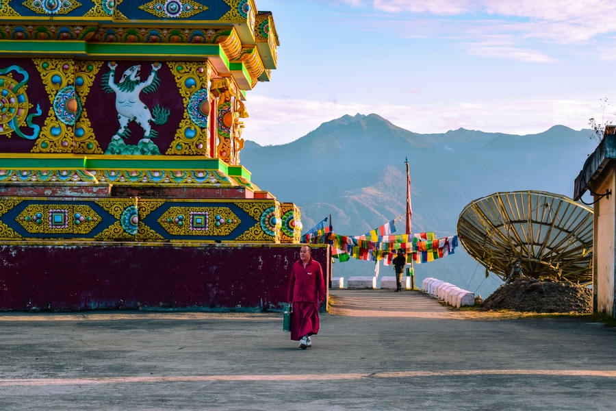 A Buddhist monk walking past the vibrant, decorated walls of a monastery in Tawang, Arunachal Pradesh, one of the 19 best places to visit in December 2026.