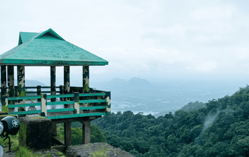 Scenic view from an offbeat hilltop watchtower overlooking the misty Pothundi reservoir valley in Nelliyampathy, showcasing hidden hill stations in South India 2026.