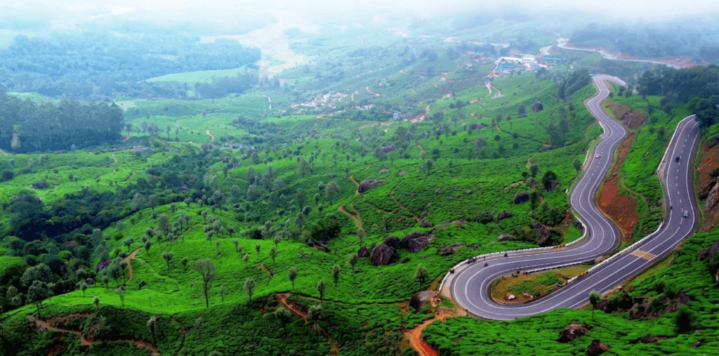 Aerial view of winding mountain roads through green tea gardens at Lockhart Gap, a top activity to do in Munnar.