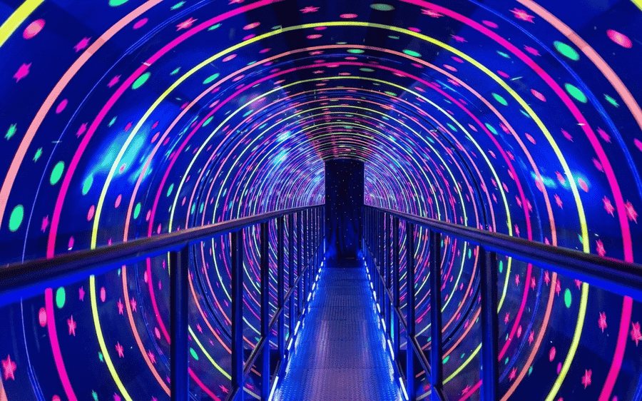 Looking through a vibrant, glowing vortex tunnel with neon lights at GRS Fantasy Park, featured among the top 19 best places to visit in Mysore.