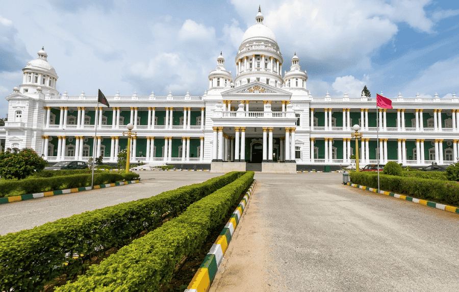 A high-quality photo of the grand front facade of the Lalitha Mahal Palace in Mysore, India, with its white domed architecture and green pillars, featured among the top 19 best places to visit.