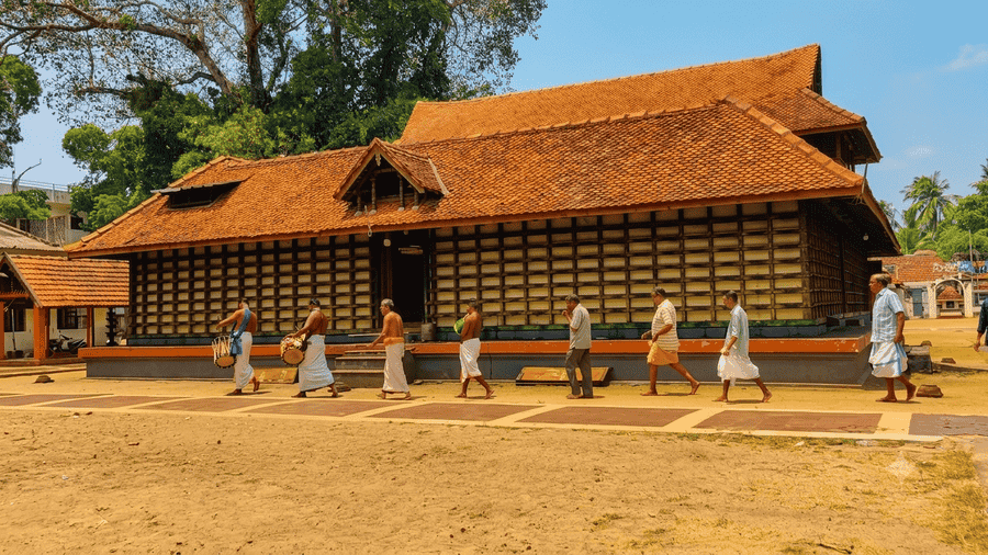 Devotees and musicians walking along the traditional wooden architecture of Mullakkal Rajarajeswari Temple, highlighted as one of the Best Places to Visit in Alleppey.