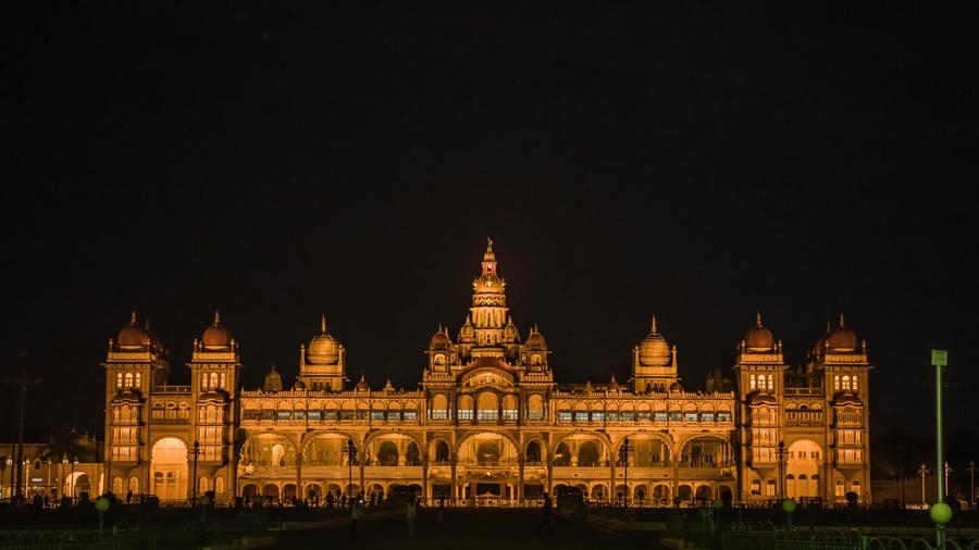 Grand Mysore Palace fully illuminated in warm golden lights at night, featured among the top 19 best places to visit in Mysore.