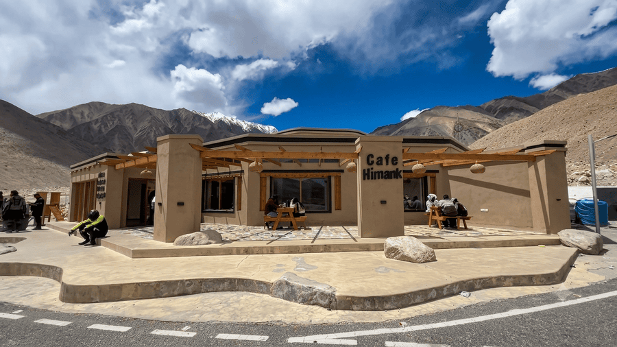 Travelers taking a relaxing break at Cafe Himank along the scenic Pangong Lake to Leh return journey, a key stop featured in our ultimate Leh Ladakh Itinerary.