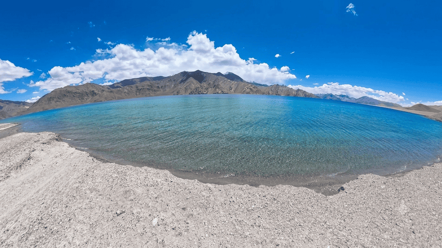 Panoramic view of the vibrant blue Pangong Lake surrounded by rugged mountains, a central destination on a Leh Ladakh Itinerary.
