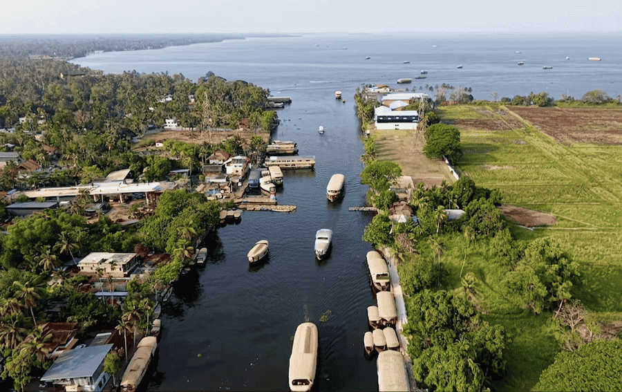 An aerial view of houseboats cruising through Punnamada Lake toward the open backwaters, highlighted as one of the Best Places to Visit in Alleppey, Kerala.