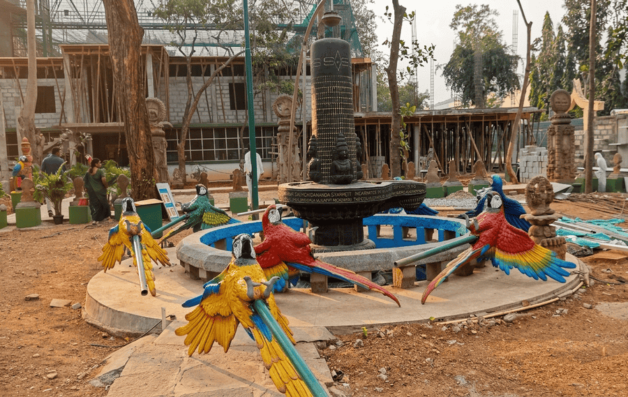Colorful parrot sculptures surrounding a central Shiva Linga fountain inside Shuka Vana, featured among the 19 best places to visit in Mysore.