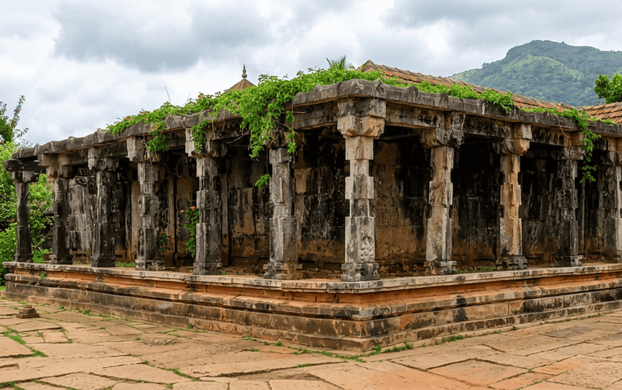 An ancient stone-pillared structure of the historic Thirunelli Temple surrounded by greenery and hills, making it one of the Best Places to Visit in Wayanad for heritage and spiritual tourism.
