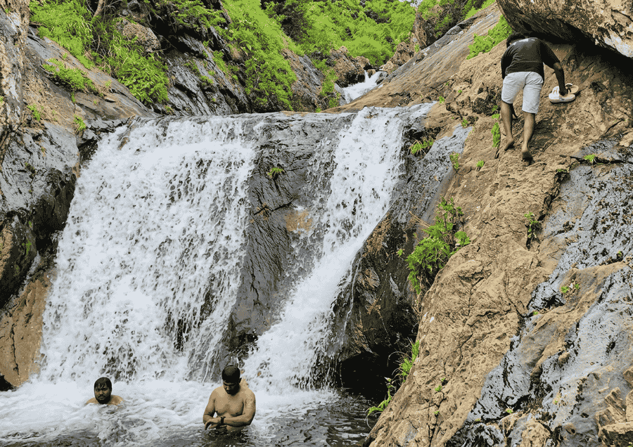 A vibrant scene at Ranajilleda Waterfalls in Araku Valley, showing visitors exploring the natural rock formations, featured as one of the best places to visit Araku Valley.