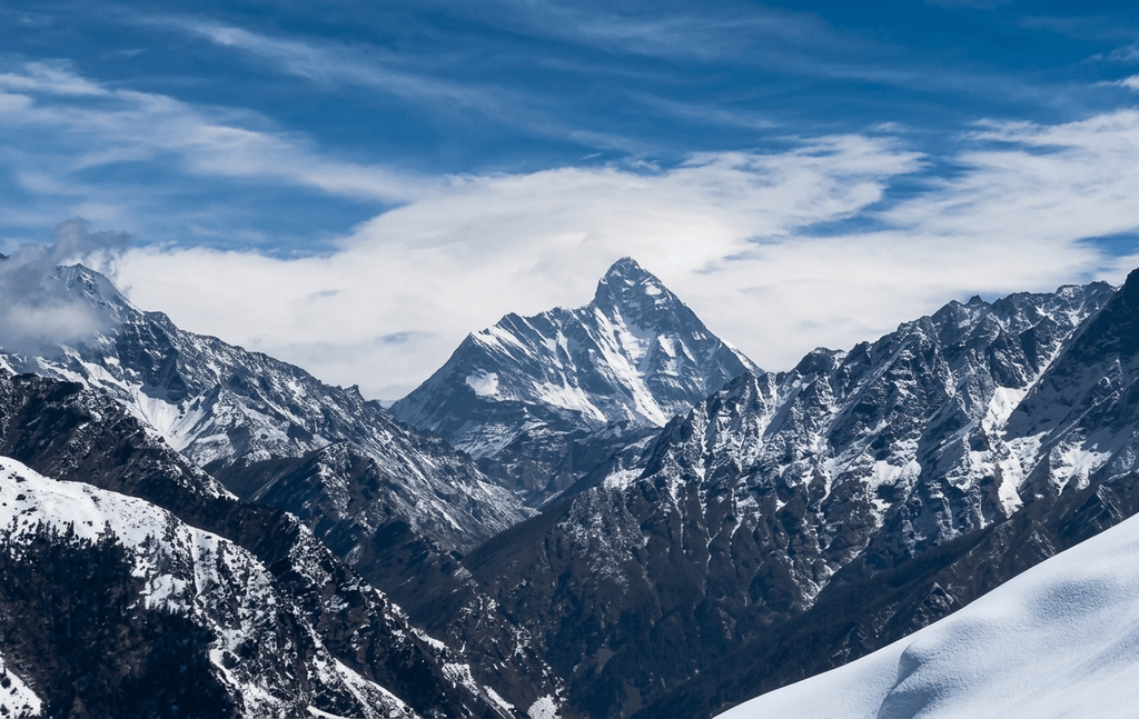 Panoramic landscape of pristine snow slopes and surrounding peaks at Auli, Uttarakhand, featured among the best places to visit Uttarakhand.