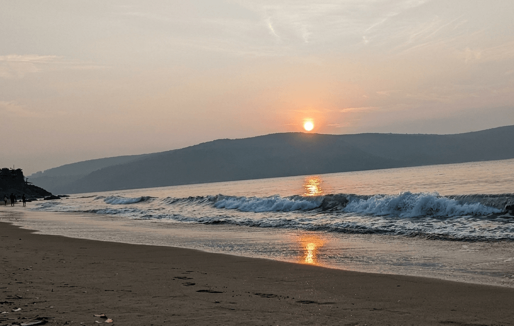 Golden sunrise sky above the mountains and sea at Belekan Beach - best places to visit Gokarna guide