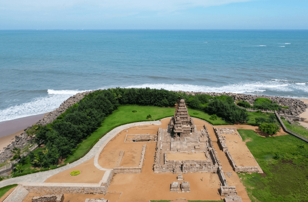 The iconic stone architecture of the Shore Temple, situated on the coastline with the turquoise sea in the background, a must-see and featured among the best places to visit Mahabalipuram.