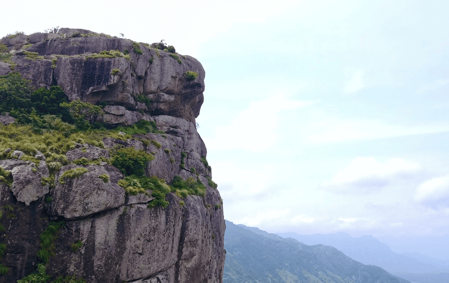A scenic view of steep mountain rock faces and valley mist at Ramakkalmedu near Thekkady, showcasing one of the best places to visit in Thekkady.