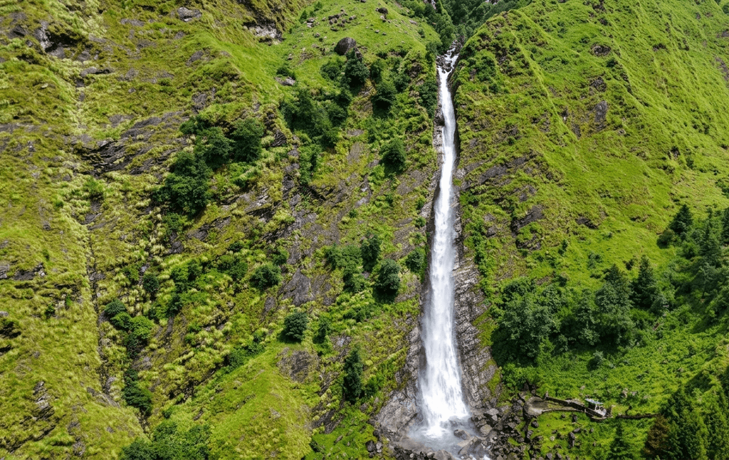 Tall natural waterfall cascading down green cliffs in Mukteshwar - best places to visit Uttarakhand guide