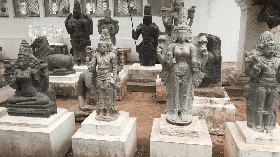 A indoor collection of historical stone and granite deity sculptures on pedestals at the Puducherry Museum (Pondicherry Museum). This cultural site is widely recognized as one of the best places to visit Pondicherry for history enthusiasts and antique art lovers.