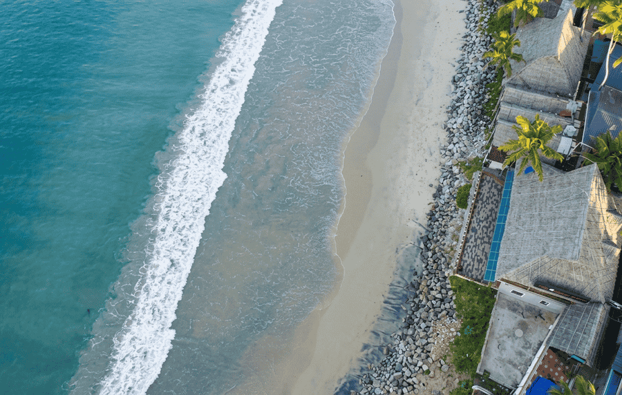 Aerial perspective of scenic Thiruvambadi Beach, featuring visible beachside resorts, seafoam, and palm trees—a highlight for travelers researching the best places to visit in Varkala.