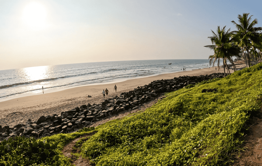 Tranquil view of Odayam Beach near Varkala, featuring palm trees, a sandy coastline, and a rocky breakwater at sunset—one of the best places to visit in Varkala for peace.